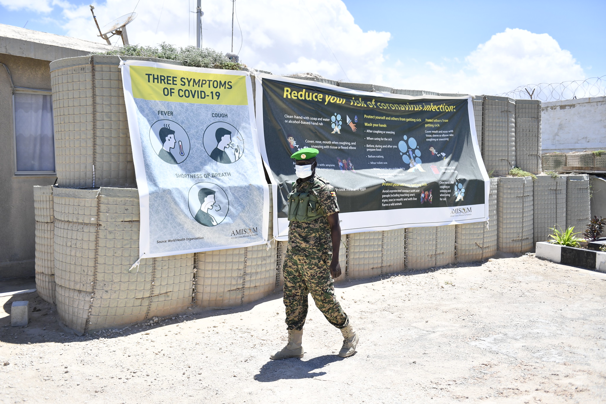 A Ugandan AMISOM soldier walks past a Covid-19 banner at the Sector One headquarters in Mogadishu, Somalia on 26 April, 2020. AMISOM Photo/Steven Candia