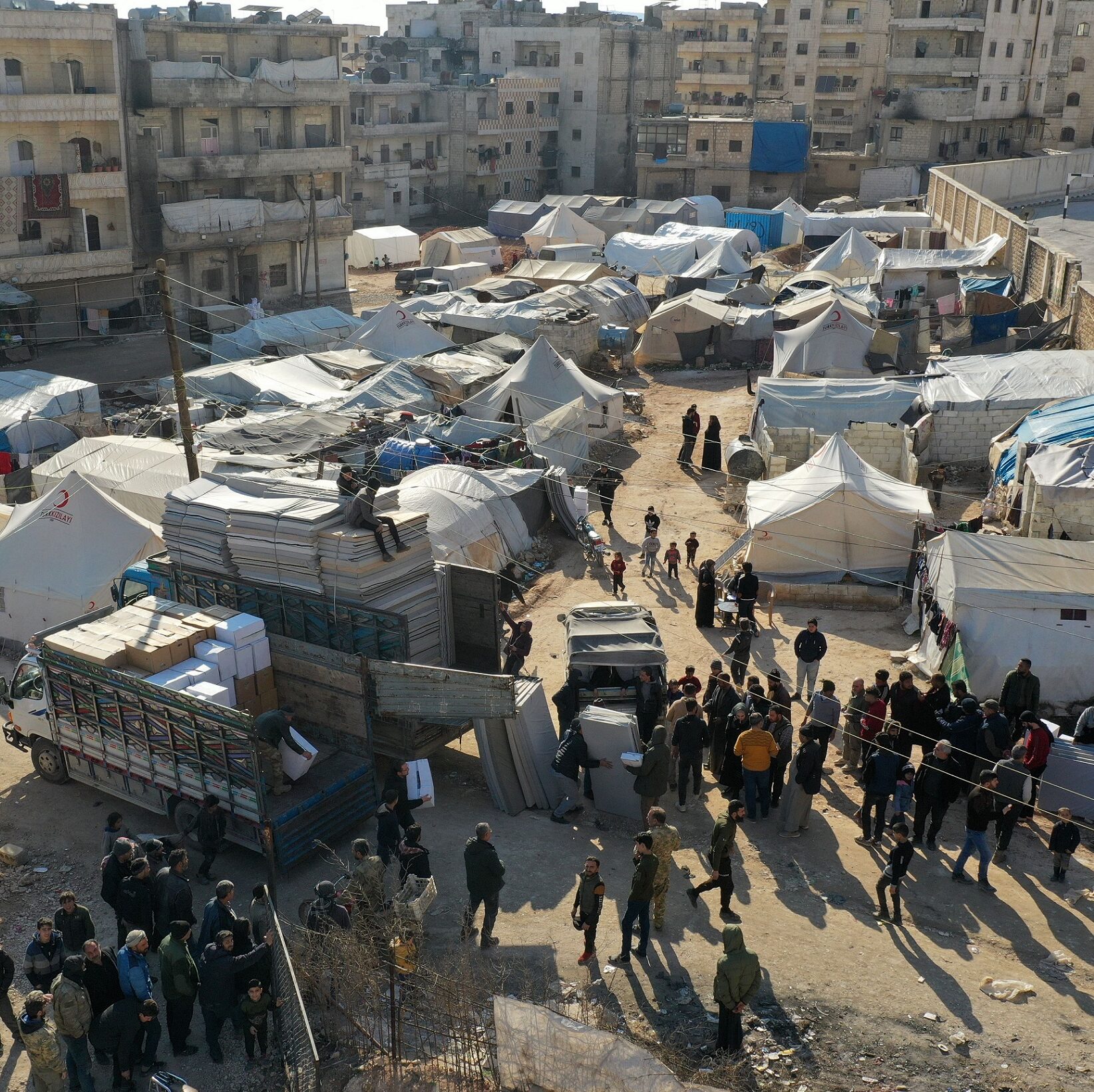 Aerial view of people who are living in tents receiving mattresses and other humanitarian aid distributed by an NGO, in the city of Afrin in the rebel-held part of Aleppo province on February 16, 2023. (Photo by Omar HAJ KADOUR / AFP) (Photo by OMAR HAJ KADOUR/AFP via Getty Images)