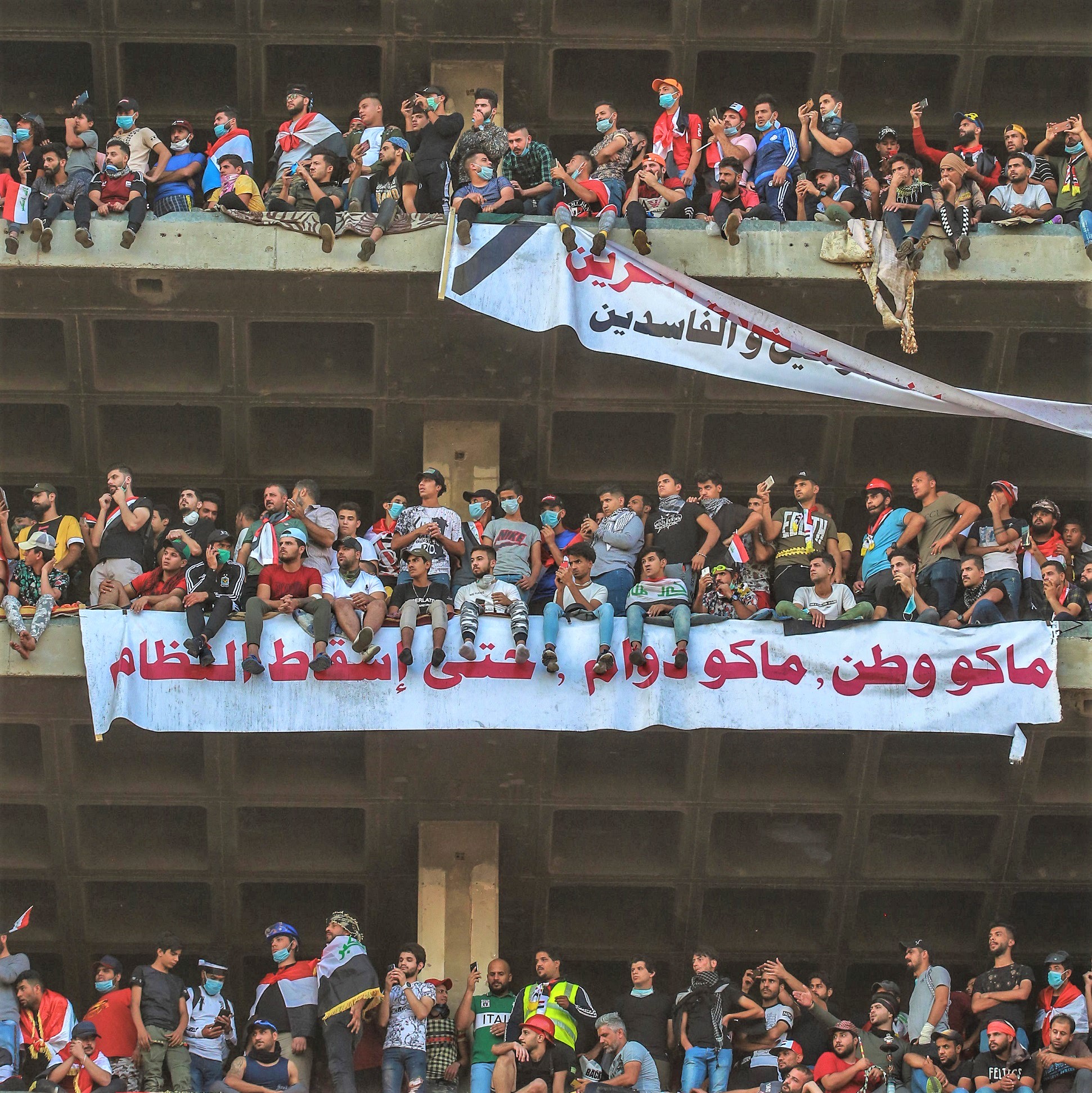 Protesters with slogans on banners take part in an anti-government demonstration near Baghdad’s Tahrir Square, November 2019. Source: Ameer Al Mohammedaw/dpa/Alamy Live News