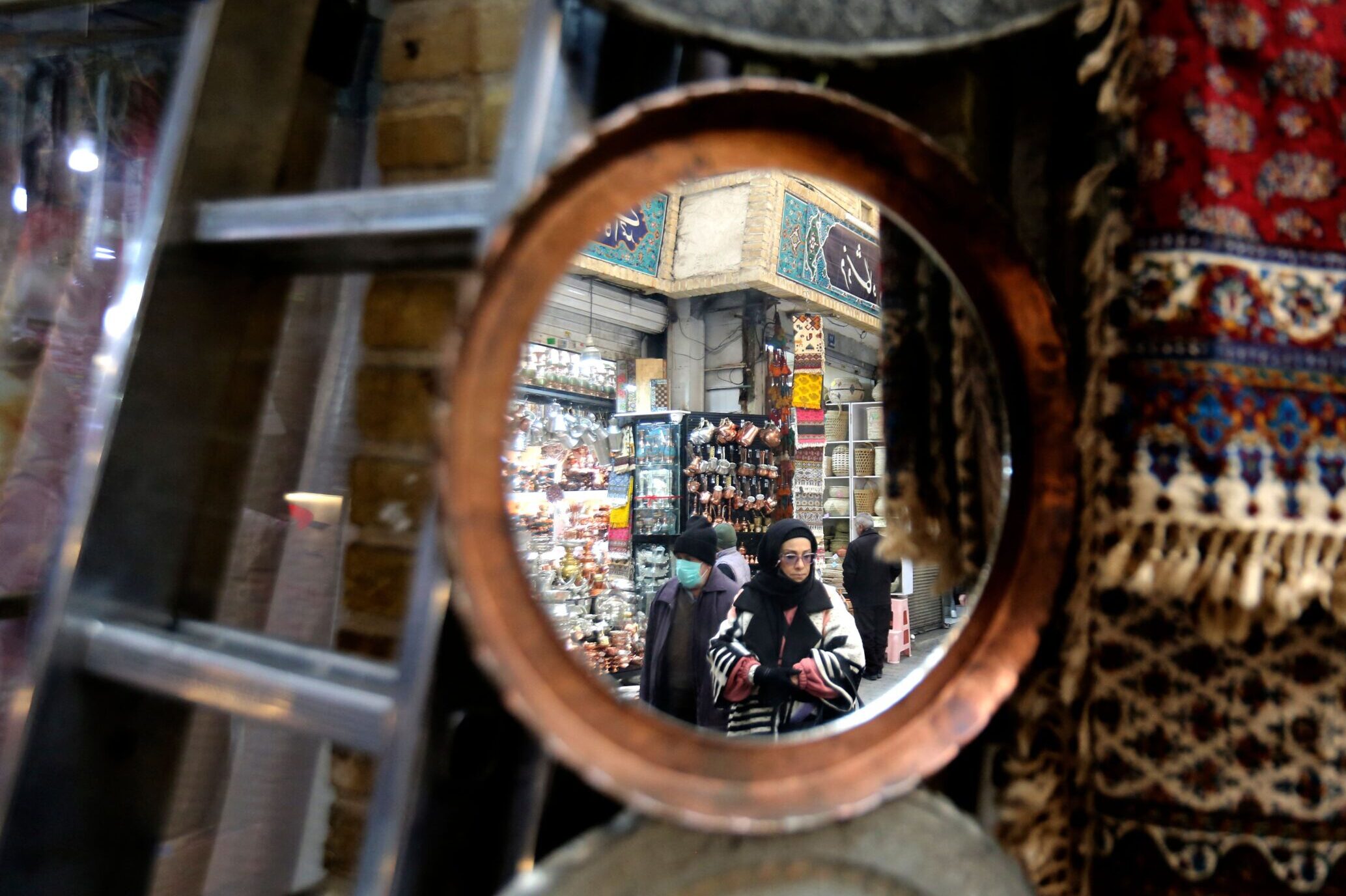 A wall mirror's reflection shows Iranians shop at the bazaar of Tajrish in northern Tehran, Iran, January 2023. Photo by ATTA KENARE / AFP via Getty Images
