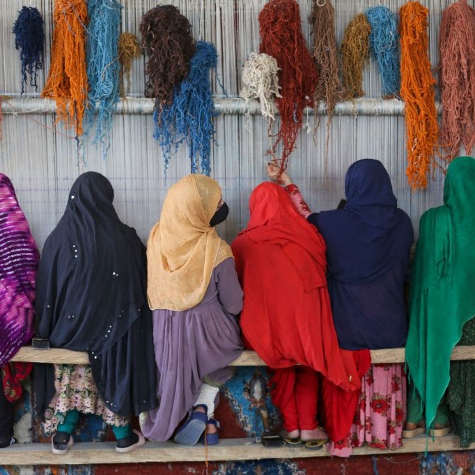 Women wearing hijabs weave carpets at a training centre in Jalalabad, Afghanistan (February 2023). Photo by Shafiullah KAKAR / AFP via Getty Images