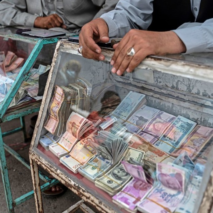 Afghan money changers wait for customers along a street near the currency exchange Sarai Shahzada market in Kabul (May 2022)