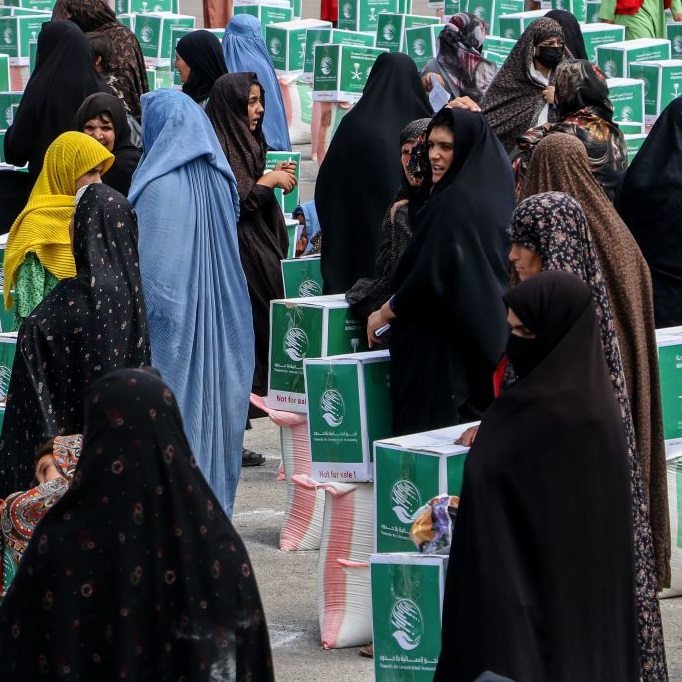 Afghan women gather around aid parcels containing food items, distributed by the King Salman Humanitarian Aid and Relief Centre in Herat (June 2023)