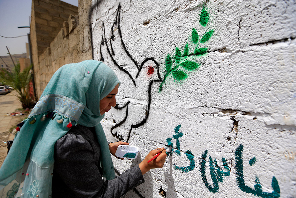 Yemeni artist paints a pro-peace graffiti on a wall