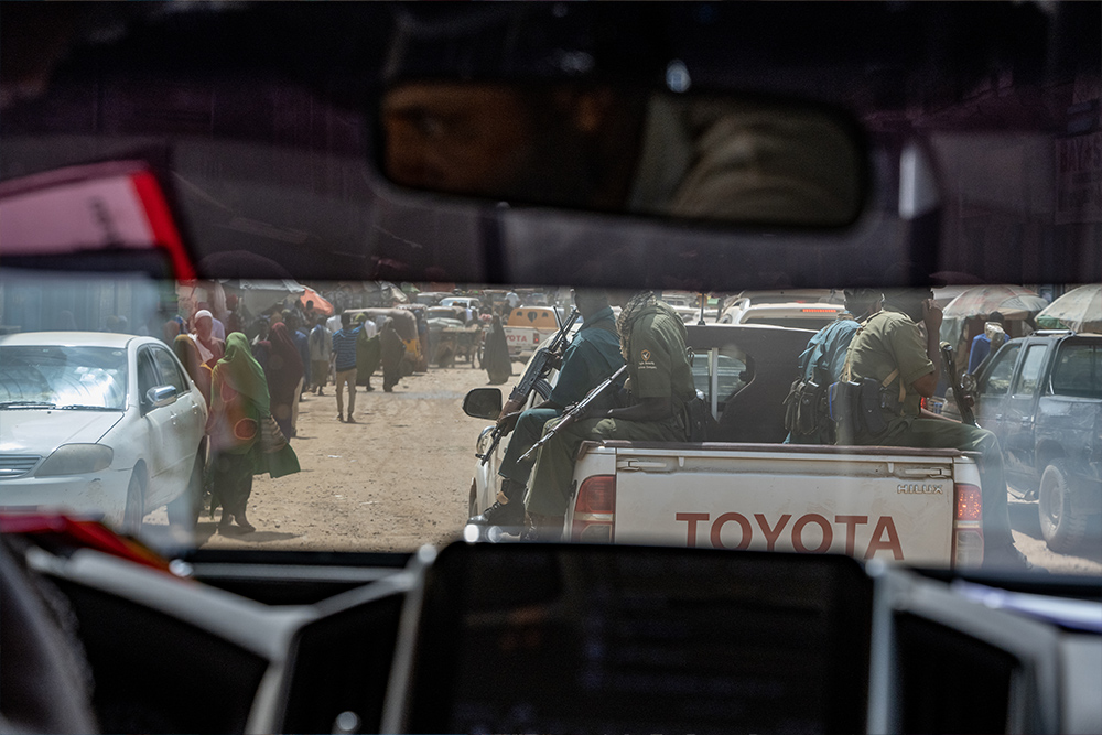 Somali security guards escort an armored vehicle through busy streets in Baidoa, Somalia