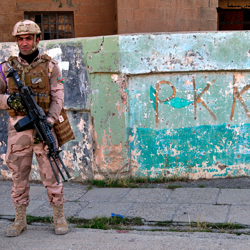 Iraqi army soldier stands next to graffiti left by an affiliate of the Kurdistan Worker’s Party, or PKK, which had recently withdrawn from Sinjar, 4 December 2020.
