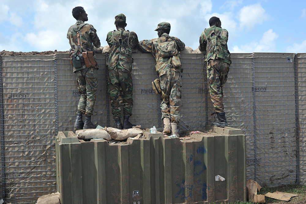 Somali soldiers on patrol look over a wall