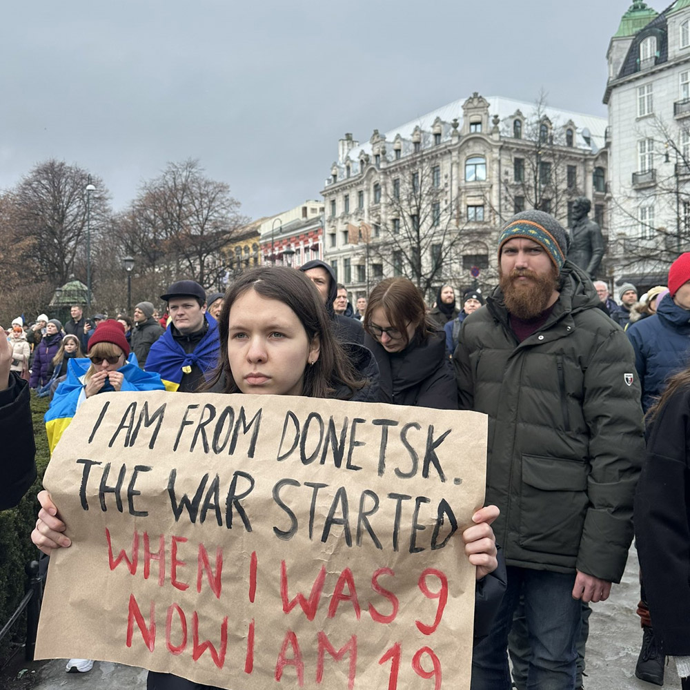 A woman holding a sign protesting the war in Ukraine