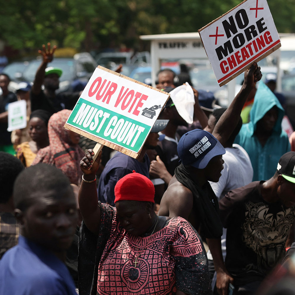 Protesters hold signs against election corruption