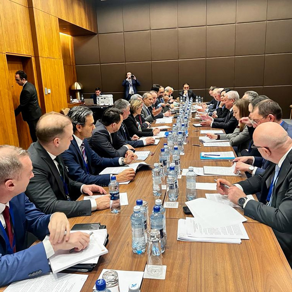 Delegates sit at a long table to discuss Syrian peace