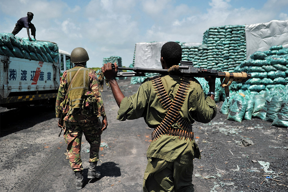 Militia walk through a charcoal loading area in Somalia
