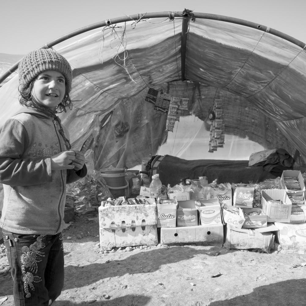 A Syrian child stands outside a rustic shop